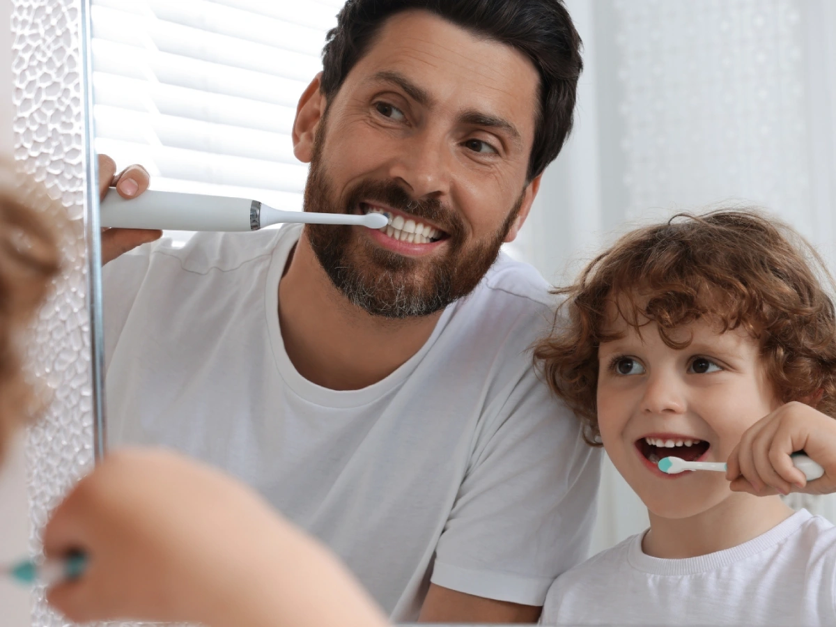 un niño y su padre cepillandose los dientes
